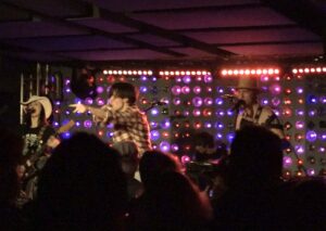 mary shelley, a rock band performing in front of purple lights