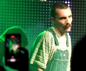 guy in overalls and striped shirt onstage